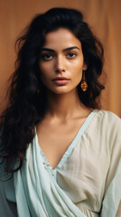 Naklejka premium Beautiful young woman with long curly hair looking at camera on brown