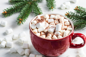 Obraz na płótnie Canvas New Year's drink. a large red mug with cocoa and a piece of white marshmallow, on the background of a table with a Christmas tree branch