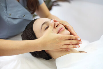 Fototapeta na wymiar Crop massage therapist massaging face of client