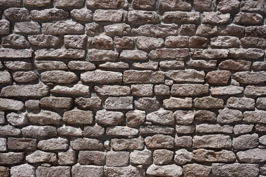 Irregular pretty pinky grey stone wall under the sun. Chile, South America.