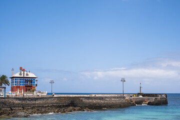 Seascape. Dock of the fishing village of Arrieta, Lanzarote. Chinese house. Blue sky with clouds. Landscape