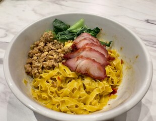 close up of traditional chinese yellow flat fried pork noodle Chasiu Charsiew Chasio Jasio barbecued bbq pork of china hongkong fusion indonesia cuisine dish