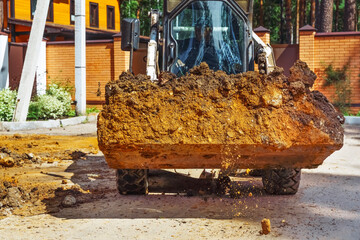 Fototapeta premium Loading soil with an excavator at a new construction site. Backhoe Digging at Construction Site.