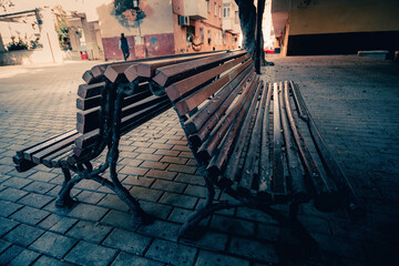 two lonely old wooden benches facing each other back to back in a poor, humble neighbourhood