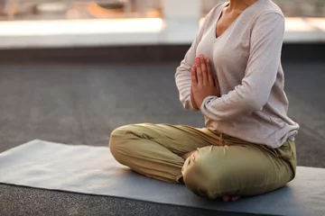 Foto op Plexiglas Woman sitting in lotus pose on mat and practicing yoga, female meditating outdoors © Dasha Petrenko