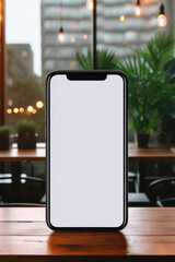 Smartphone with blank screen on wooden table in cafe. Mock up