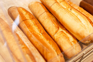 Fresh crispy baguettes on a wooden counter in a store. Close-up.