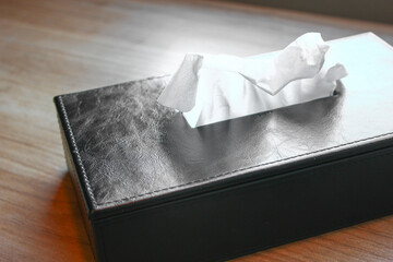Crumpled napkin in a black leather case on a wooden table