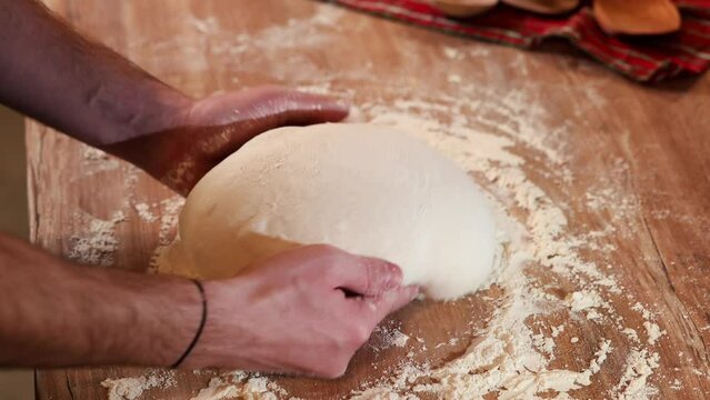 Shaping the sourdough. 4K video view from above with male hands while shaping a home made bread dough after the first rise. Home made fresh bread making process.