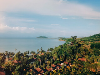 Aerial view of red roofs of houses, palms and ocean. Tropical landscape on island