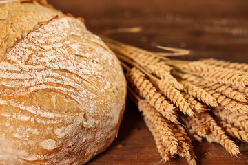 Bread baking photo. Close up view of some ears of wheat next to a fresh bread out of the oven with wheat shape scored on the dough. Delicios bread home cooking.