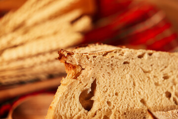 Slices of a delicious home made bread. Bread baking photo in a beautiful setup with ears of wheat in background. Fresh bread on the wooden counter top.