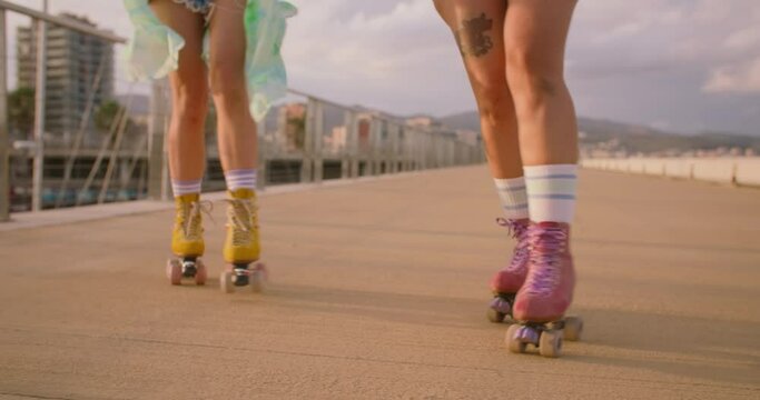 Two women dancing and do tricks on rollerblades. Forever young and free spirits concept. Joy of life and happy summer. Self-expression through sports and fashion. Outdoor activity. 
