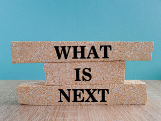 What is next symbol. Concept word What is next on brick blocks. Beautiful blue background, wooden...