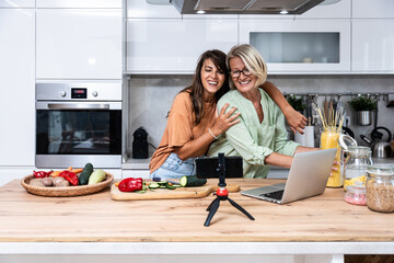Grandma and daughter record a cooking vlog or podcast while chopping vegetables for a healthy...