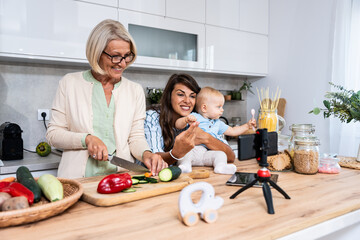 Three Generations Family. Grandma, mother and baby record a cooking vlog or podcast while chopping...