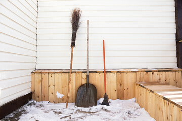 A broom, a shovel and a cleaver are tools for clearing snow from the yard after a cold winter.
