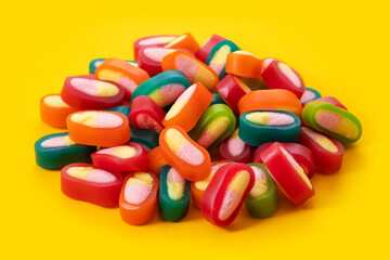 Piles of delicious colorful jelly candies on yellow background