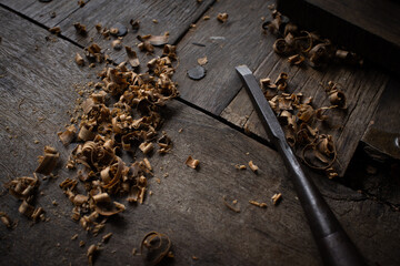 A carpenter carves wood with a chicel



