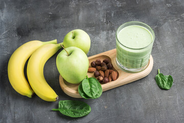 Green detox smoothie in a glass, blended vegetarian drink from spinach leaves, apple, banana fruit...