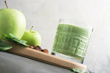 Green detox smoothie in a glass, blended vegetarian drink from spinach leaves, apple, banana fruit...