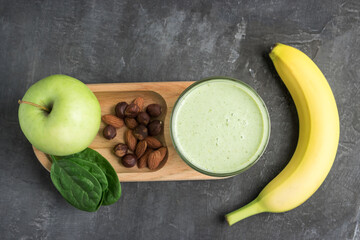 Green detox smoothie in a glass, blended vegetarian drink from spinach leaves, apple, banana fruit...
