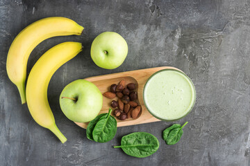 Green detox smoothie in a glass, blended vegetarian drink from spinach leaves, apple, banana fruit...