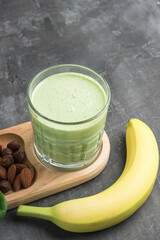 Green detox smoothie in a glass, blended vegetarian drink from spinach leaves, apple, banana fruit...