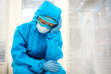 Tired depressed nurse in personal protective equipment PPE after difficult shift during Covid-19.