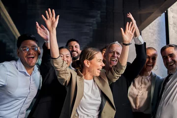 Foto op Plexiglas Diverse multiracial cheerful group of excited business people standing in office hallway having fun. Joyful colleagues celebrating success by raising hands at same time and smiling happy together © CarlosBarquero