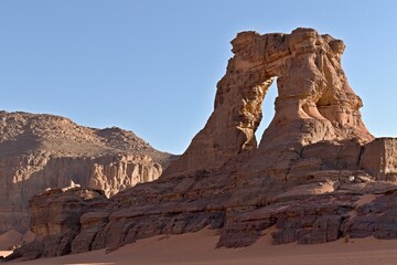 View of Tamezguida arch, rock formation in Tadrart Rouge rocky mountain range in Tassili n Ajjer National Park. Sahara desert, Algeria, Africa.