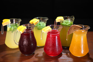 Lemonade in the jug and lemons with mint on the table indoor. Berry Lemonade. Quenching thirst and refreshing drinks. Cold lemonades.