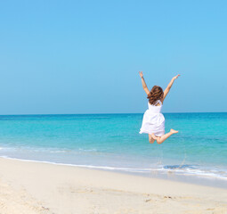 Woman in white dress jumping on the beach