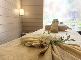 Rolled towels and flower on massage table in empty spa salon
