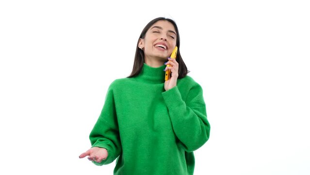 Young woman engages in a cheerful phone conversation, radiating positive vibes against a clean white background. This image captures the joy of communication .