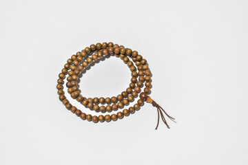 Brown wooden Mala beads on a white background ringed three times