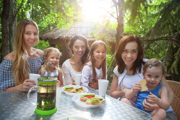 Happy mothers and her adorable little daughters at outdoors cafe