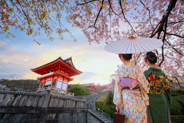 Scenic view of Young Japanese women in a traditional Kimono dress at Kiyomizu-dera temple sunrise during full bloom cherry blossom in Kyoto, Japan