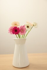 Vase with beautiful gerbera flowers on wooden table