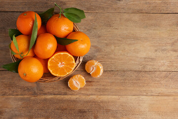 Delicious tangerines with leaves on wooden table, top view. Space for text