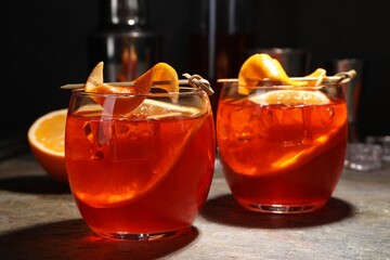 Aperol spritz cocktail, ice cubes and orange slices in glasses on grey textured table, closeup