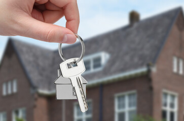 Woman holding key near house outdoors, closeup