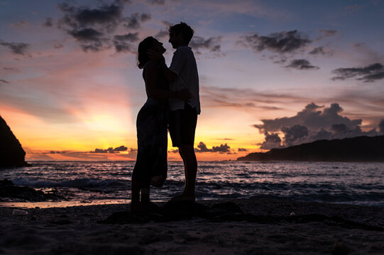Silhouette of a couple in love embracing on a tropical beach at golden hour, Bali, Indonesia