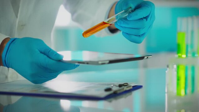 A microbiology researcher in a laboratory slowly mixes chemical liquids using test tubes. During scientific research, a microbiologist conducts an analysis while brainstorming