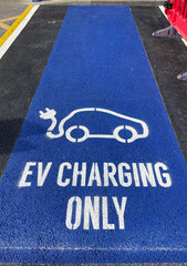 An electric vehicle charging point is indicated by tarmac painted blue with white lettering and car...