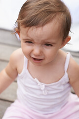 Sad baby, face and sitting outside of curious toddler, little girl or disappointed on outdoor porch. Closeup of young unhappy child, upset kid or adorable cute newborn with frowning facial expression