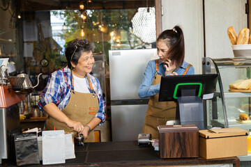 Young Asian barista female smiling happy working with retired mother bonding relationship, cafe shop small business entrepreneur woman teaching 60s senior elderly pensioner worker making hot coffee