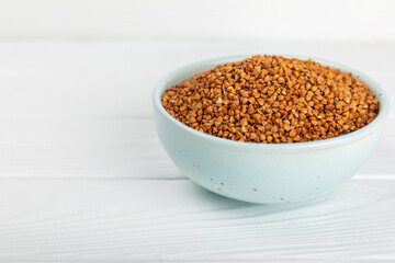 Raw buckwheat in a bowl on a textured background.Wheat grains, porridge, cereals, raw buckwheat in a plate. Healthy food. Porridge. Diet. Organic cerea. Space for text.Copy space.