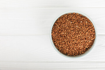 Raw buckwheat in a bowl on a textured background.Wheat grains, porridge, cereals, raw buckwheat in a plate. Healthy food. Porridge. Diet. Organic cerea. Space for text.Copy space.