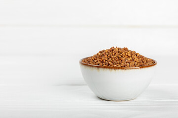 Raw buckwheat in a bowl on a textured background.Wheat grains, porridge, cereals, raw buckwheat in a plate. Healthy food. Porridge. Diet. Organic cerea. Space for text.Copy space.